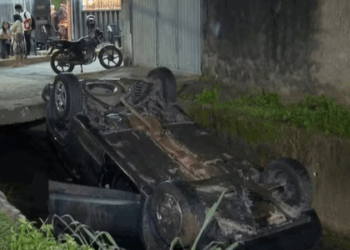 Veículo caiu em valão e deixou um passageiro ferido em Cariacica, ES. Moradores denunciam recorrência de acidentes e a ausência de sinalização na via.