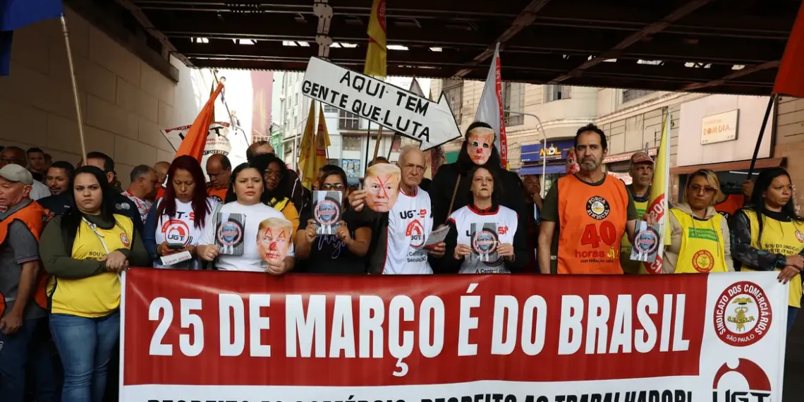Manifestantes na Rua 25 de Março, em São Paulo, reagem a tarifas de Trump e acusam o presidente dos EUA de atacar a soberania nacional. Ato organizado por sindicatos denuncia interferência e riscos à economia brasileira.