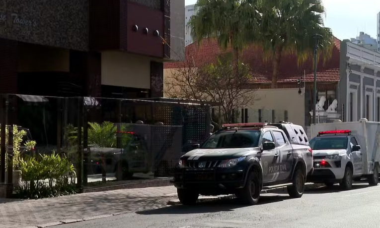 Casal estrangeiro é achado morto em cobertura no Centro de Curitiba. Polícia suspeita de feminicídio seguido de suicídio. Arma importada, drogas e seringas foram encontradas no local.