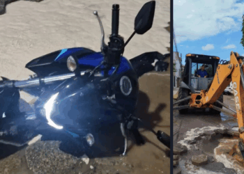 A motocicleta parcialmente “engolida” por um buraco causado por afundamento do solo após o rompimento de adutora.
