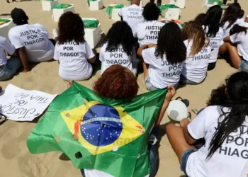 Manifestantes pedem justiça pela morte de Thiago Menezes Flausino, de 13 anos, em ato no Rio de Janeiro, no dia do início do julgamento de policiais militares acusados pelo crime.