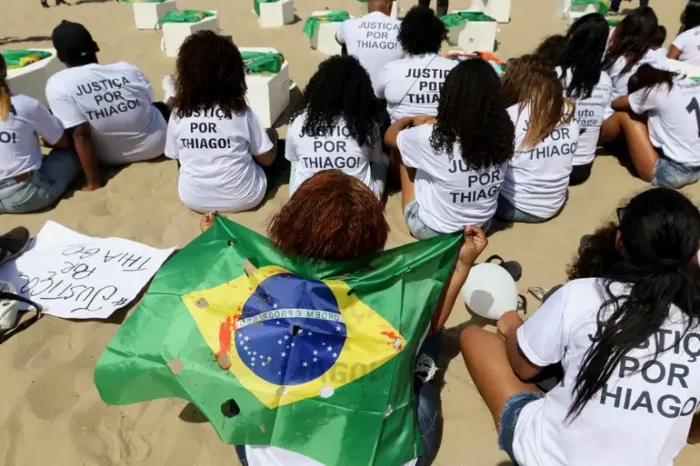 Manifestantes pedem justiça pela morte de Thiago Menezes Flausino, de 13 anos, em ato no Rio de Janeiro, no dia do início do julgamento de policiais militares acusados pelo crime.