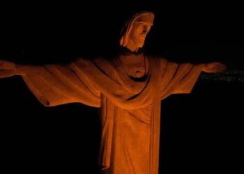 Cristo Redentor é iluminado de laranja em campanha pelos 20 anos da Lei Maria da Penha e de combate ao feminicídio.